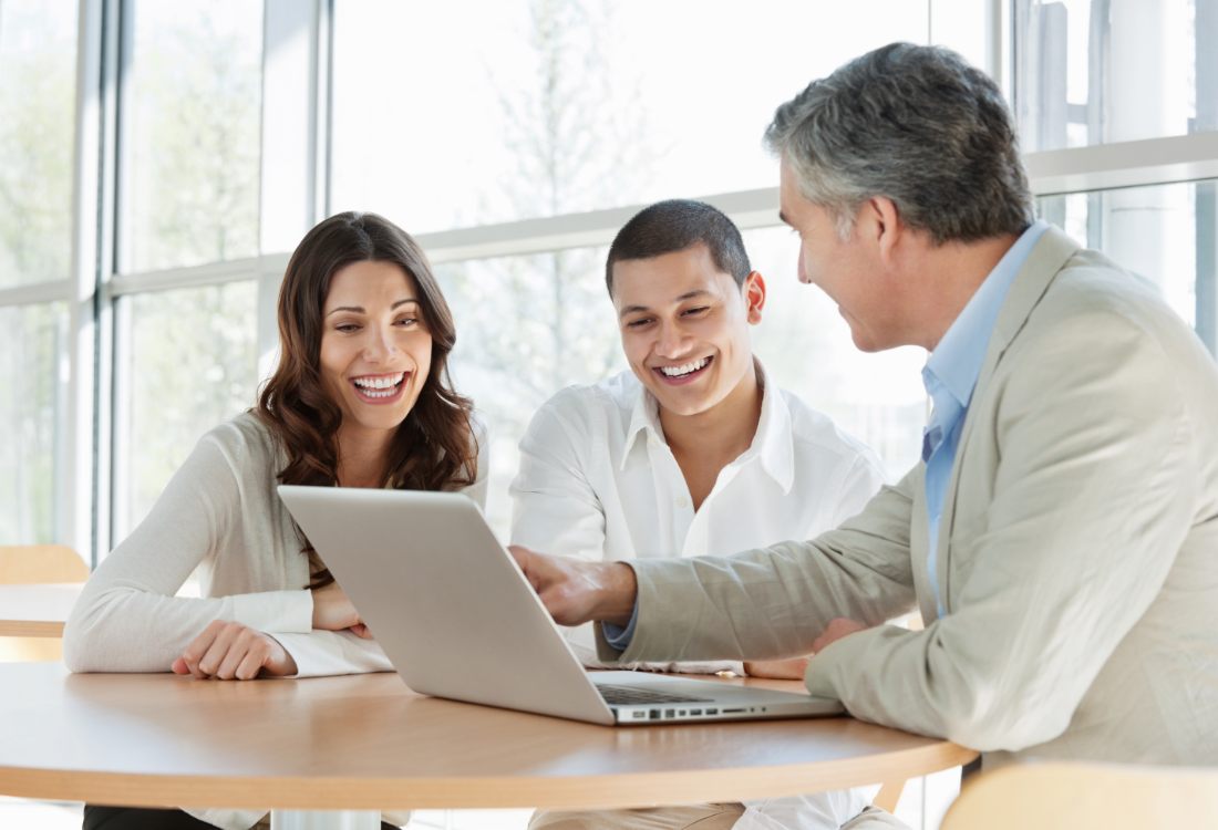 Business leader mentoring two employees with a laptop, symbolising effective leadership training evaluation.