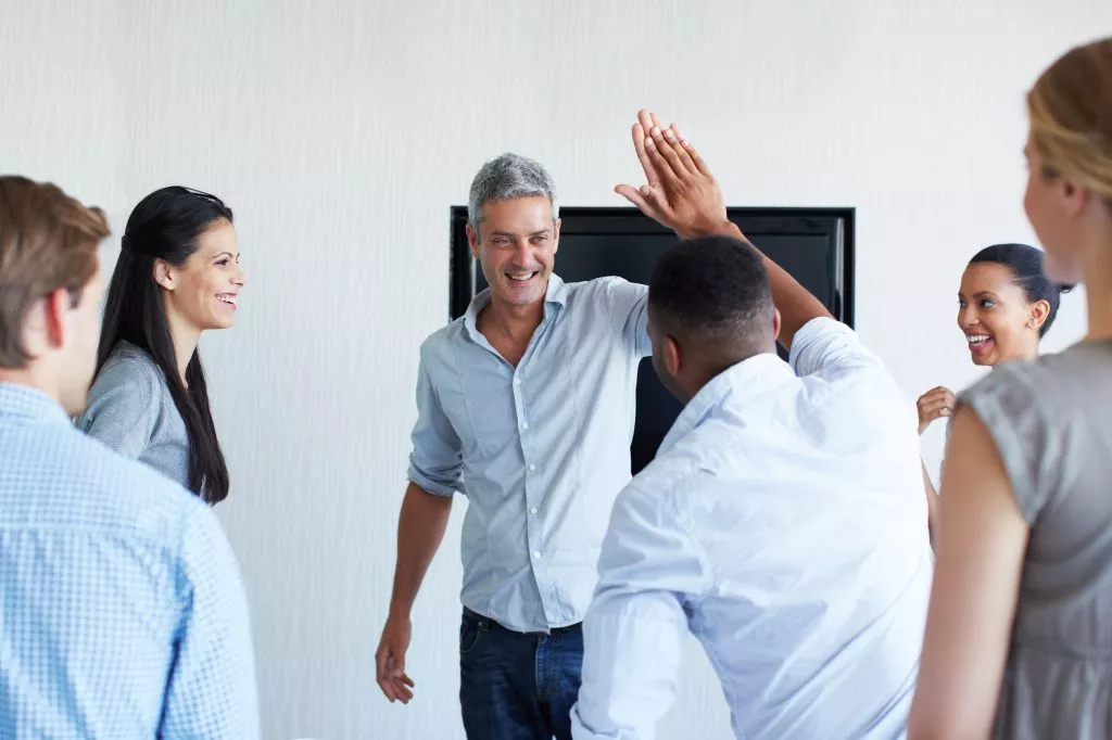 Employer high fiving employee to boost employees' morale during difficult times.