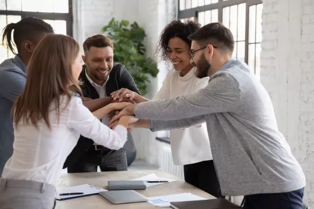 Team members stacking hands, engaged in a free team building activity