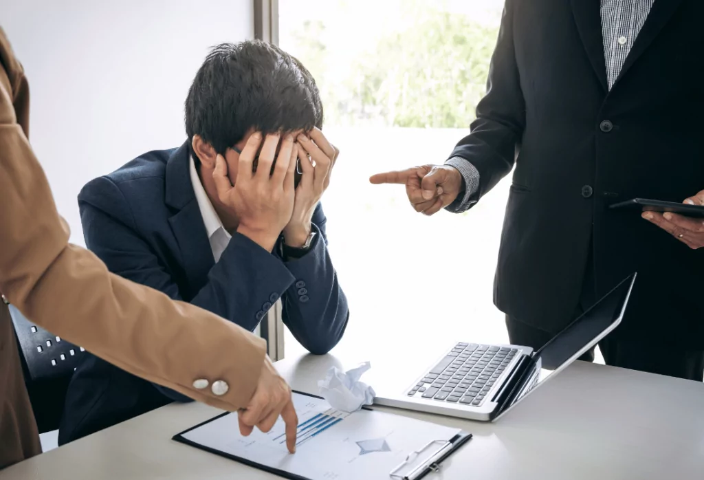 A man with his head in his hands at work who is disengaged at work. 