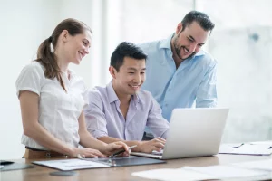 work colleagues around a laptop researching top 5 benefits of customer surveys for your organisation 